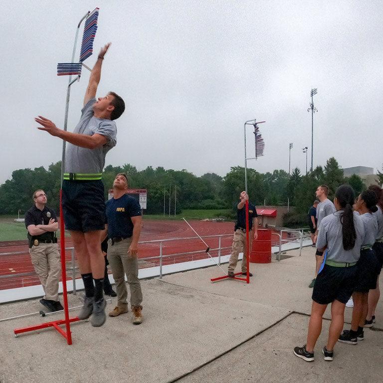 A young IUPA cadet leaps to touch the top of a pole during a physical fitness assessment