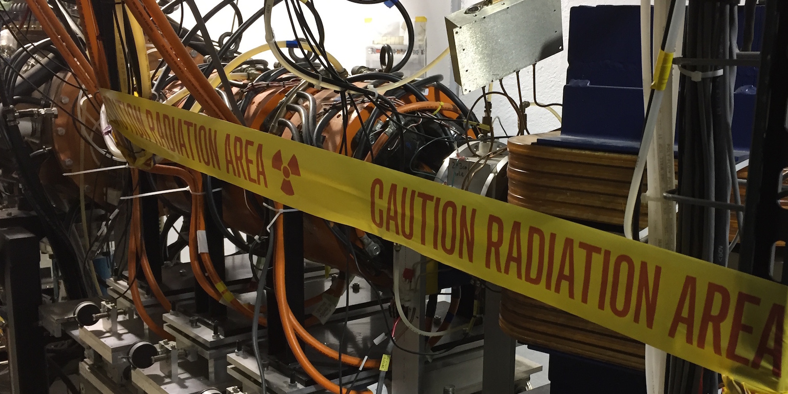 An engine surrounded by wires with yellow tape that says "caution radiation area."