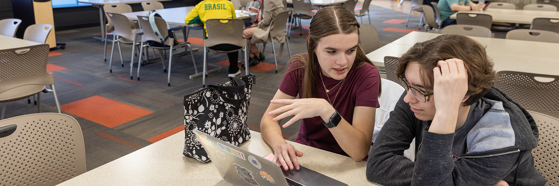 Two IU South Bend students study at a desk while viewing information on a laptop.