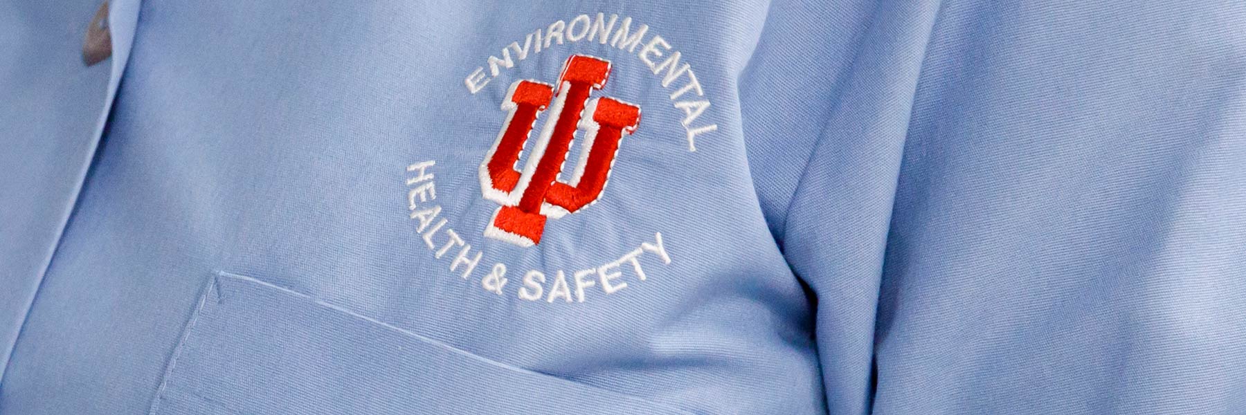 A picture of the IU EHS logo, embroidered on a pale blue lab coat. 