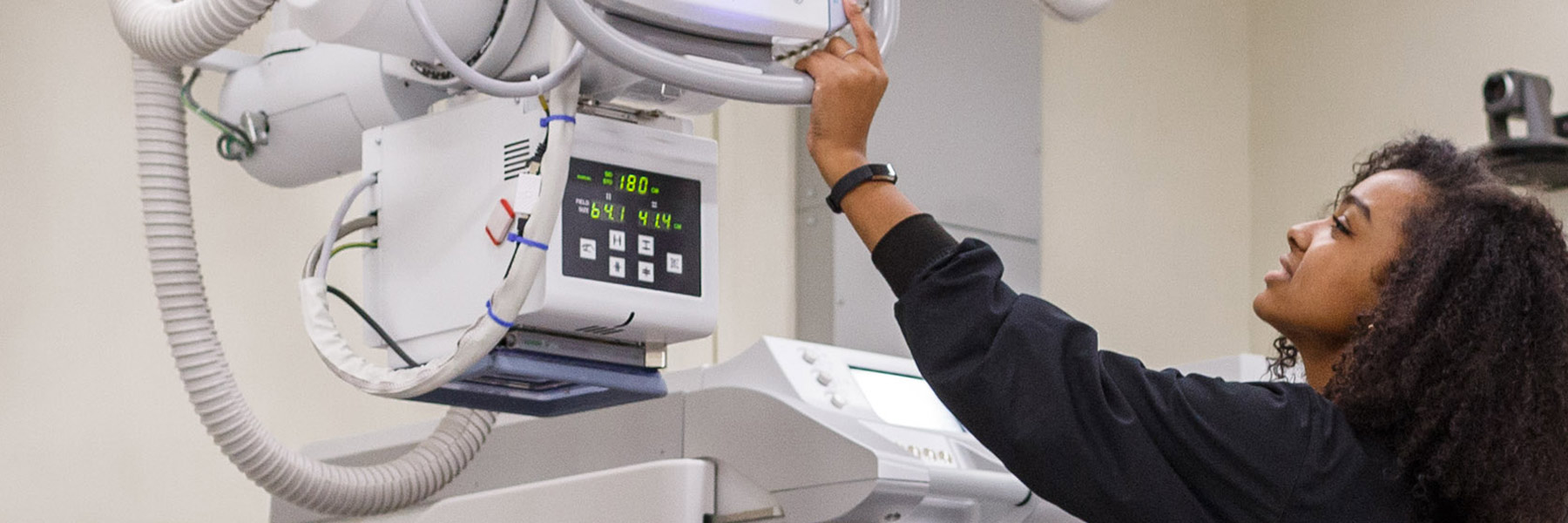 An IU nursing student in scrubs prepares an X-ray machine for a fluoroscopy scan.