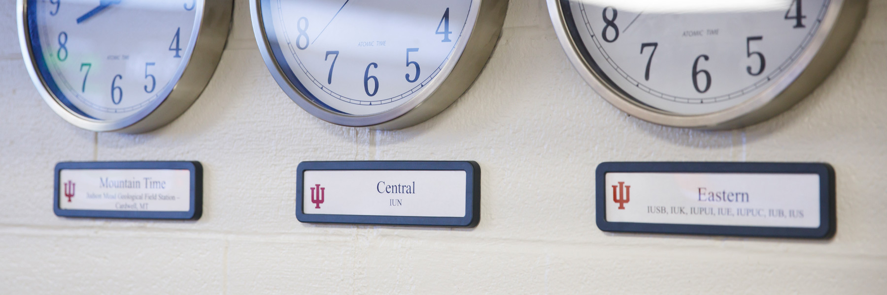 A line of wall clocks showing the time for various IU campuses. 