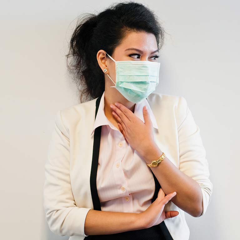 A woman with dark hair wearing a blue surgical mask