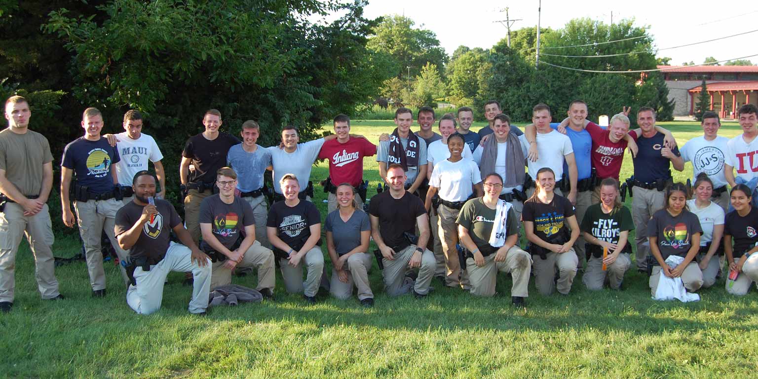 A summer outdoors group photo of the IU Police Academy cadets, a diverse and optimistic looking group of young people at home in each other's company.