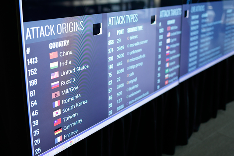 A close-up of digital screens showing current international cyber attacks. 